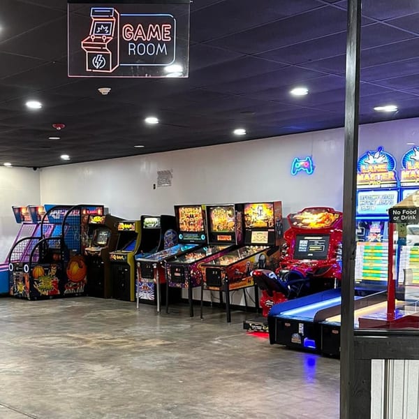 A brightly lit game room at Decades Family Restaurant, featuring various arcade games and pinball machines.