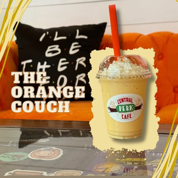 Central Perk Cafe smoothie with whipped cream and a red straw, on a table with an orange couch.
