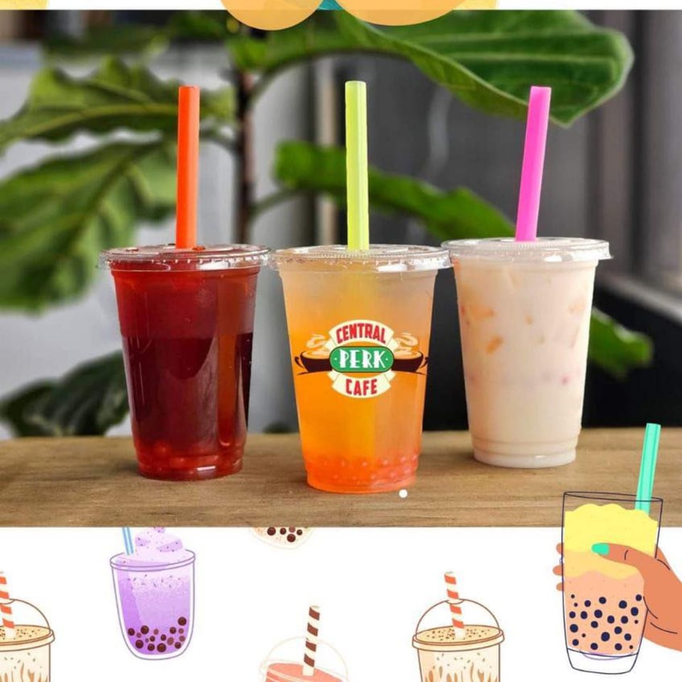 Three bubble tea drinks on a wooden surface, one with a Central Perk Cafe logo.