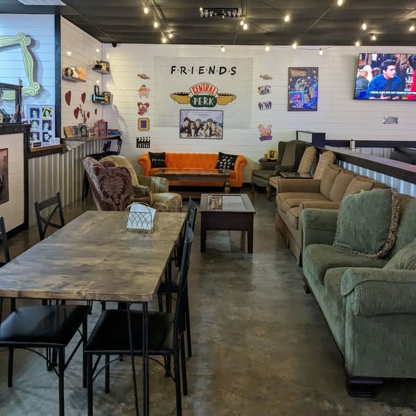 Restaurant interior with Friends TV show decor, including an orange couch, and dining tables.