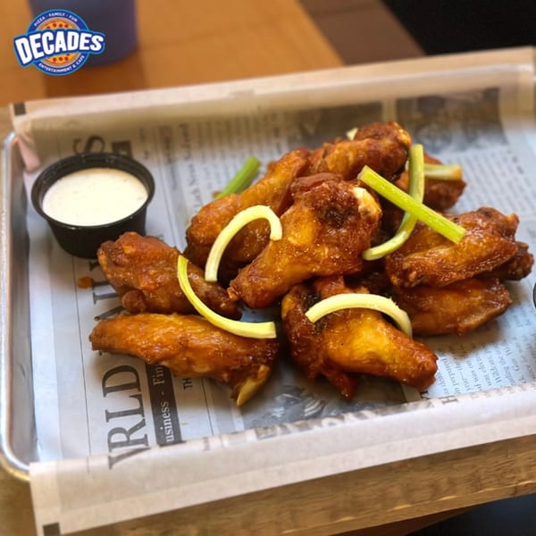 Decades Family Restaurant's crispy chicken wings with celery and ranch dressing on a newspaper-lined tray.