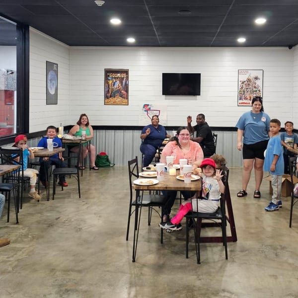 Families and children enjoying pizza and drinks at tables inside Decades Family Restaurant.