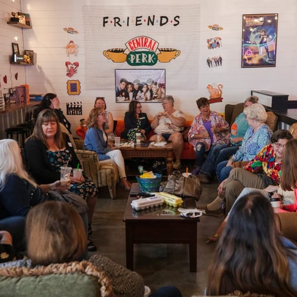 Women gathered in a cozy restaurant lounge area with Friends TV show decor on the wall.