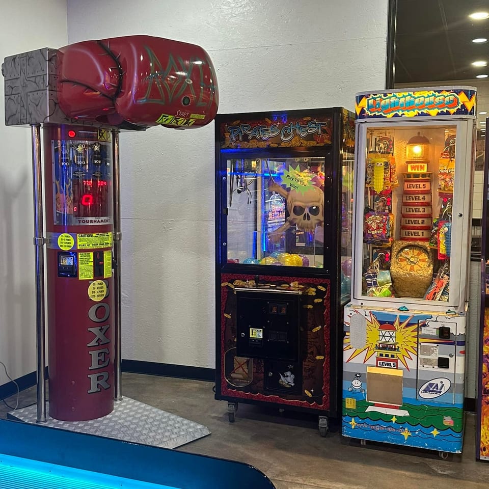 Arcade games, including a boxing machine, claw machine, and prize game, at Decades Family Restaurant.