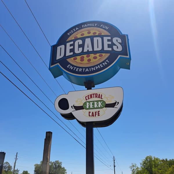 Decades Family Restaurant sign with a pizza graphic and a Central Perk Cafe sign below it.