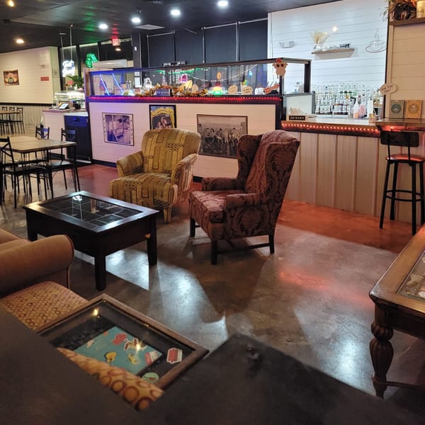 Cozy seating area with patterned armchairs, coffee tables, and a bar in Decades Family Restaurant.