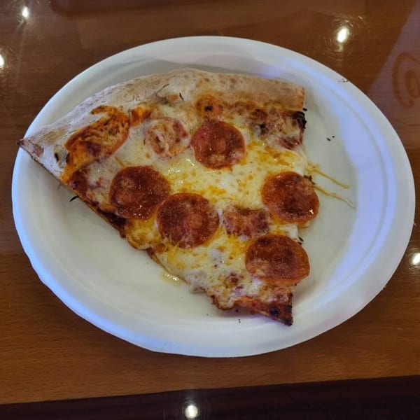A single slice of pepperoni pizza with melted cheese on a white paper plate.