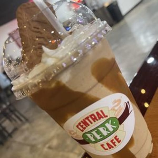 A Central Perk Cafe branded iced coffee drink with whipped cream and a chocolate cookie.