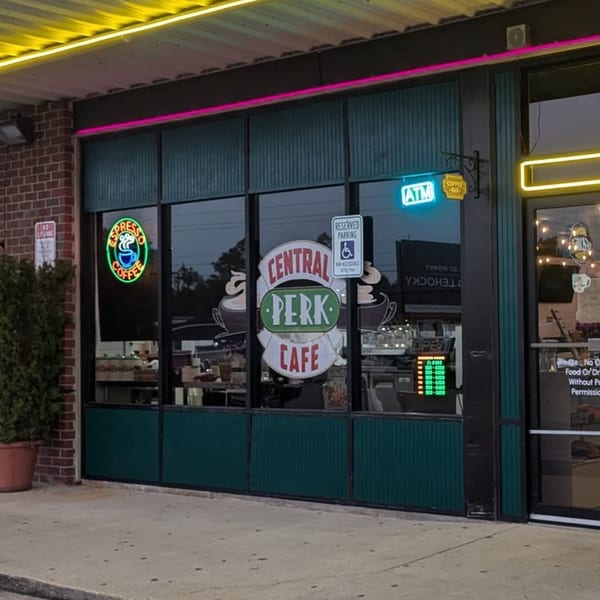 Exterior of Decades Family Restaurant with a Central Perk Cafe sign and neon lights.