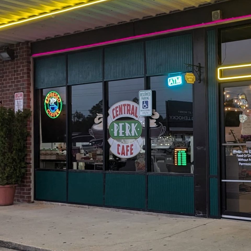 Exterior of Decades Family Restaurant with a Central Perk Cafe sign and neon lights.