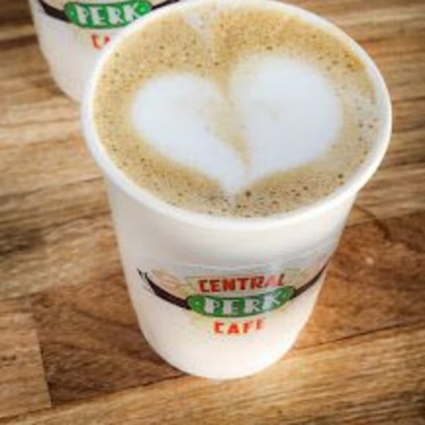 A Central Perk Cafe branded cup of latte with a heart design in the foam.