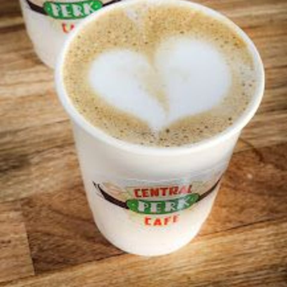 A Central Perk Cafe branded cup of latte with a heart design in the foam.