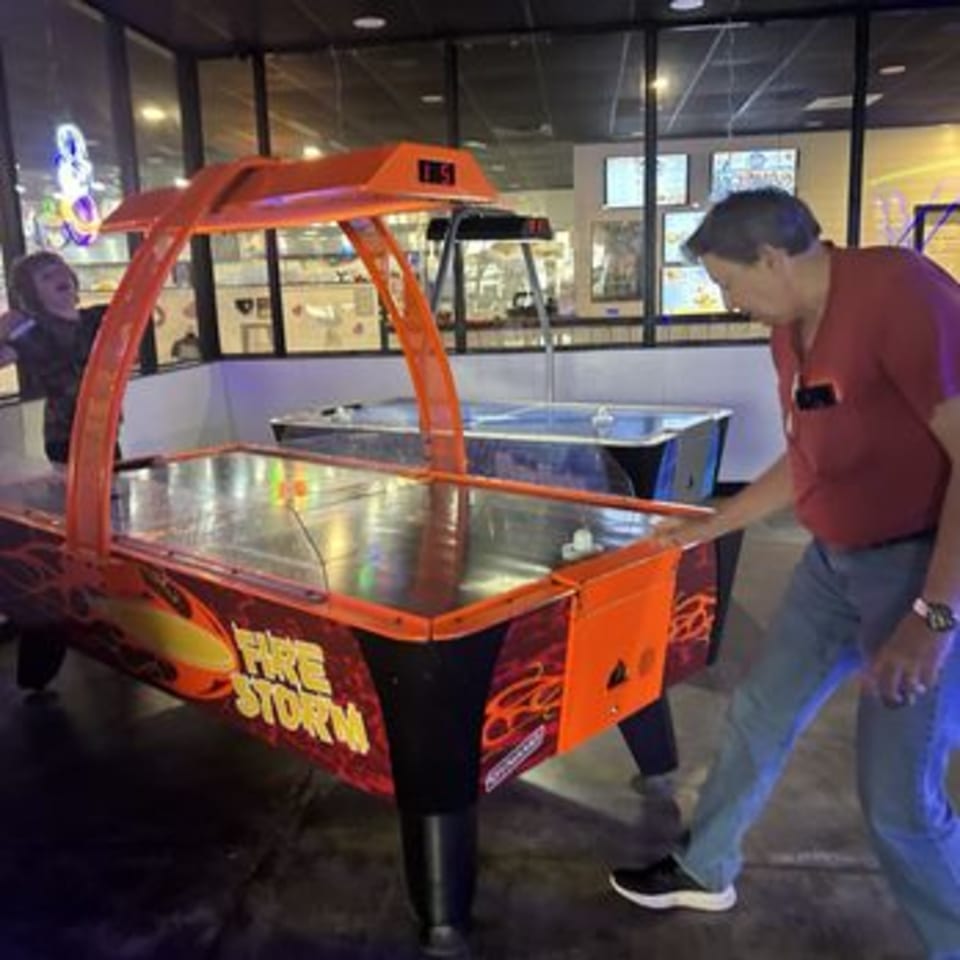 Two people playing air hockey on a "Fire Storm" table at Decades Family Restaurant.