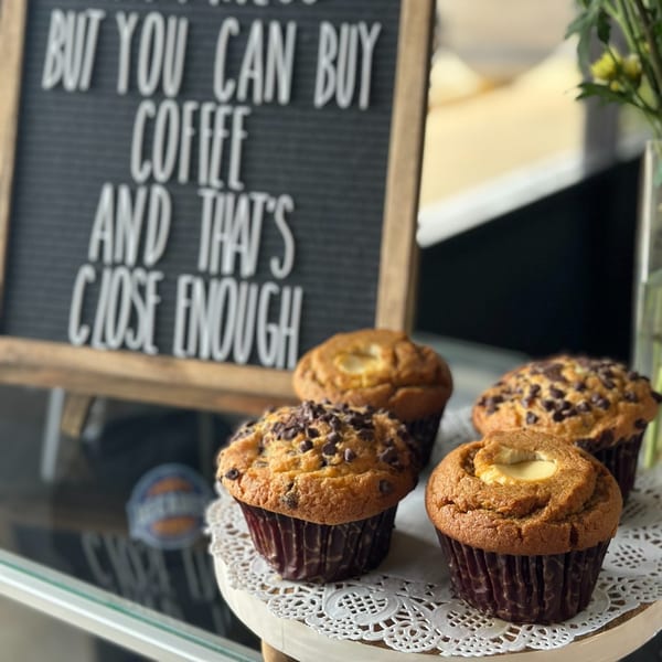 Four muffins, two chocolate chip and two cream cheese, on a white lace doily stand.